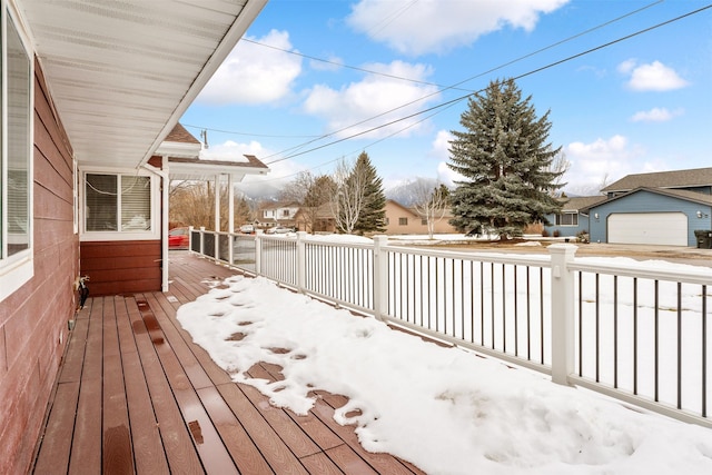 snow covered deck featuring a garage and a residential view