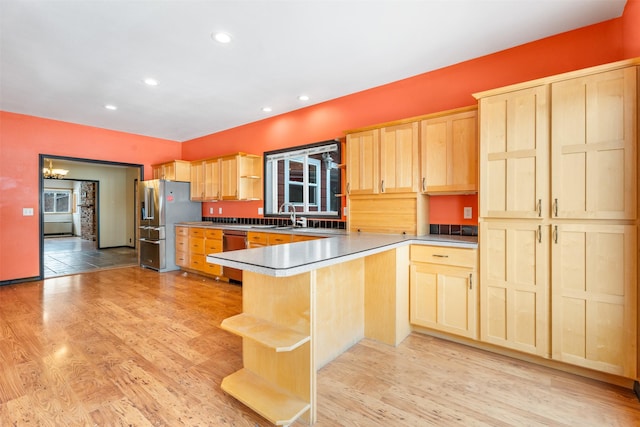 kitchen with a peninsula, light wood-type flooring, and light brown cabinets