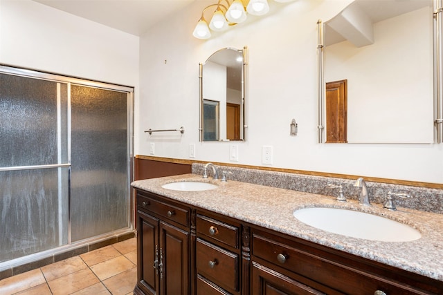 bathroom with tile patterned flooring, a sink, a shower stall, and double vanity