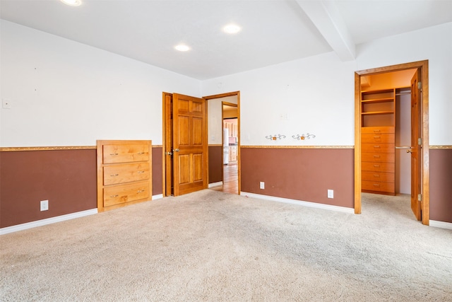 unfurnished bedroom featuring light colored carpet, a spacious closet, beam ceiling, a closet, and recessed lighting