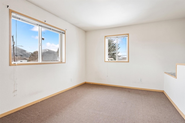 unfurnished room featuring carpet and baseboards