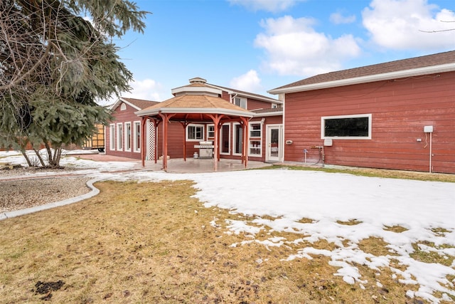 snow covered back of property featuring a yard and a gazebo