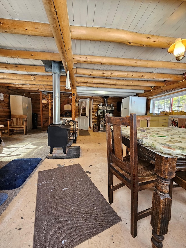 dining space featuring log walls, beam ceiling, and a wood stove