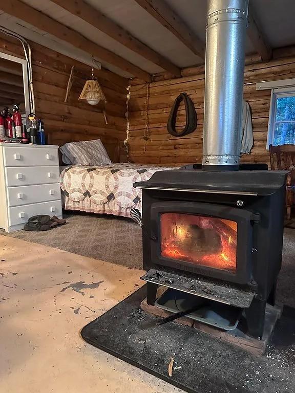 details featuring a wood stove, beamed ceiling, and log walls