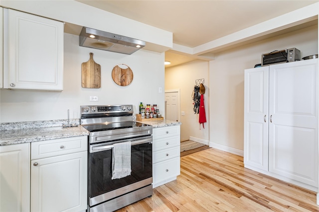 kitchen featuring white cabinetry, baseboards, light wood-style floors, wall chimney exhaust hood, and stainless steel range with electric stovetop