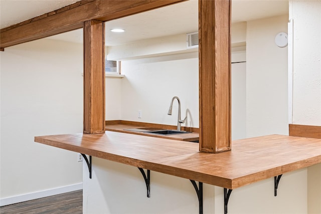 kitchen with visible vents, baseboards, butcher block countertops, dark wood-style flooring, and a sink