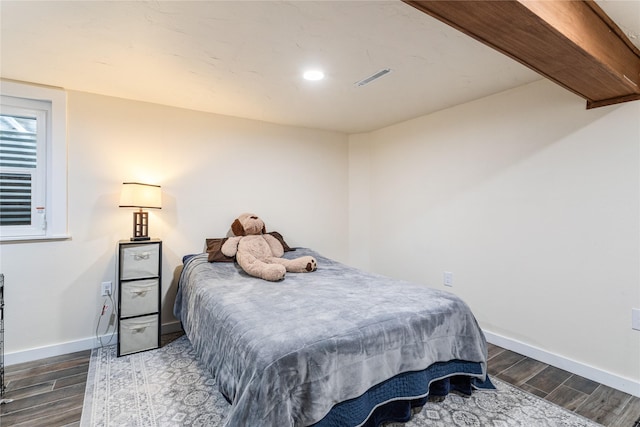 bedroom with visible vents, baseboards, and wood finished floors