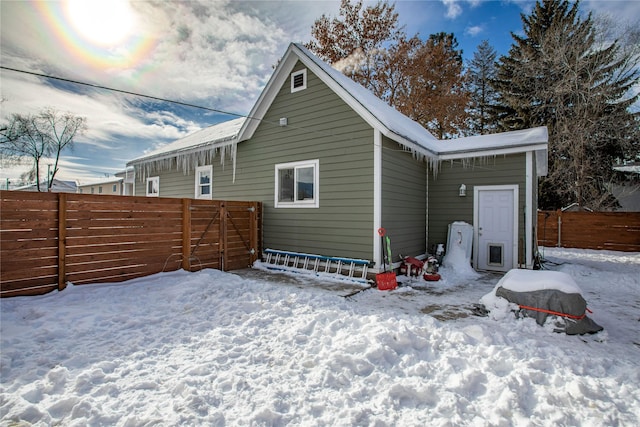 snow covered rear of property featuring fence