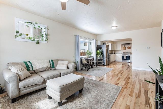 living room featuring light wood finished floors, ceiling fan, and baseboards