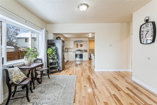 dining space featuring light wood-type flooring and baseboards