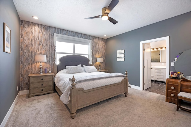 bedroom with baseboards, connected bathroom, ceiling fan, a textured ceiling, and carpet flooring