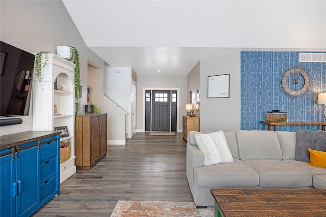 living area featuring dark wood finished floors, visible vents, an accent wall, baseboards, and wallpapered walls