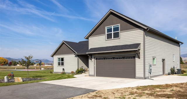 view of front of house featuring central AC unit, concrete driveway, an attached garage, a mountain view, and a front yard