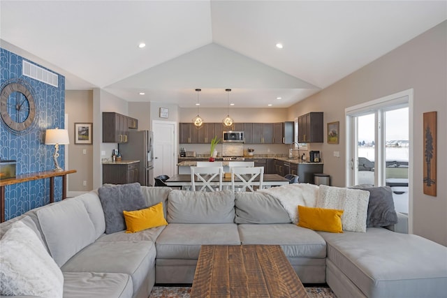 living room with an accent wall, recessed lighting, and vaulted ceiling