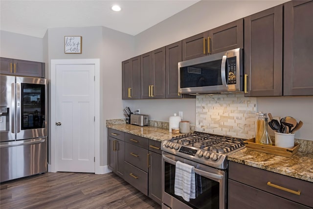 kitchen featuring stainless steel appliances, dark wood-type flooring, backsplash, and light stone countertops