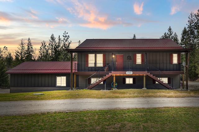 view of front facade featuring a porch, a front yard, metal roof, and stairs