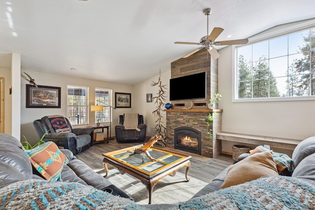 living area with a fireplace, a ceiling fan, vaulted ceiling, and wood finished floors