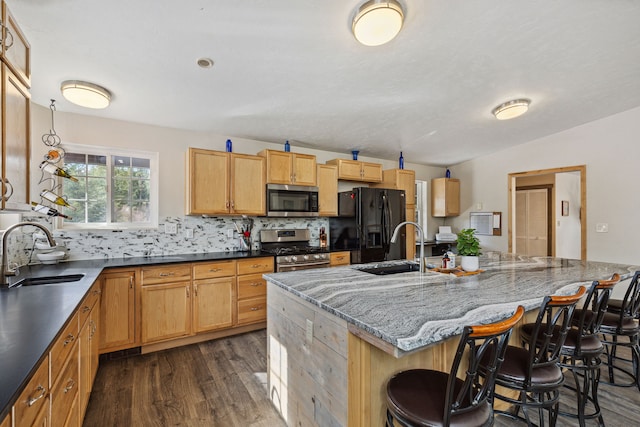 kitchen featuring a breakfast bar area, appliances with stainless steel finishes, dark wood-style flooring, and a sink