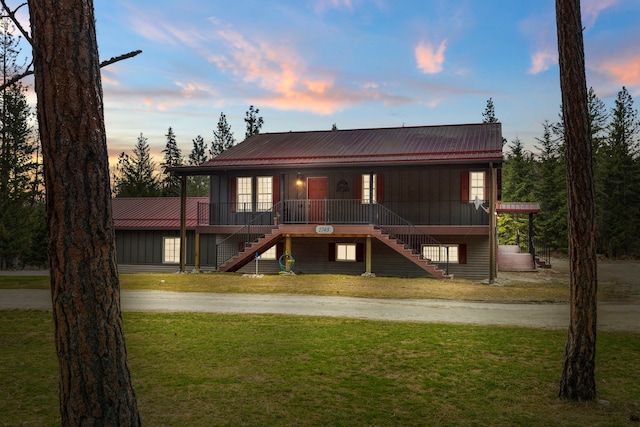 view of front facade with metal roof, stairway, and a front lawn