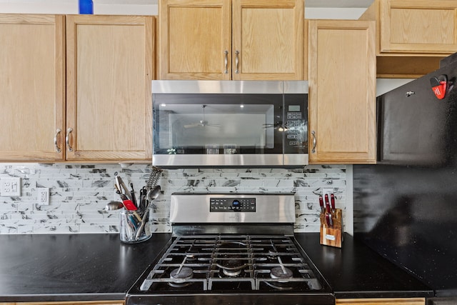 kitchen featuring stainless steel appliances, backsplash, dark countertops, and light brown cabinets