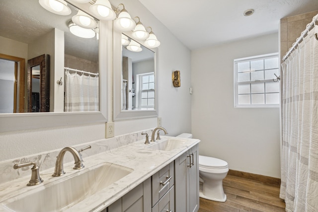 bathroom featuring baseboards, a sink, toilet, and wood finished floors