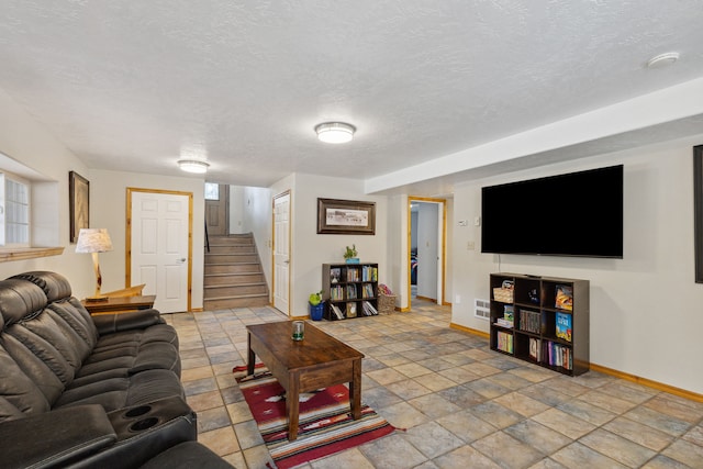 living room with a textured ceiling, stone finish flooring, stairway, and baseboards