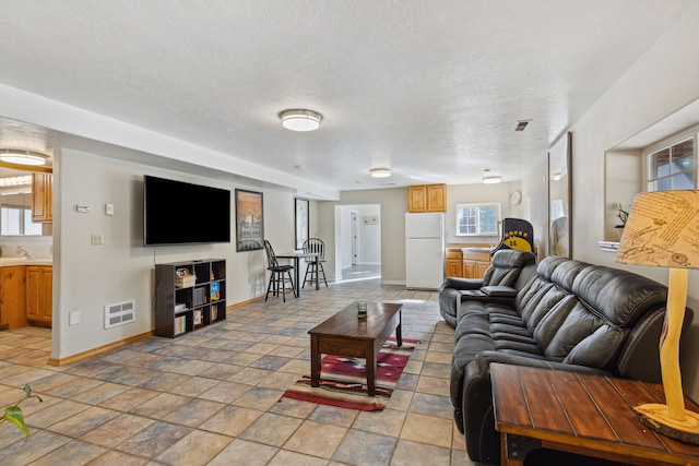 living room with a textured ceiling, visible vents, and baseboards