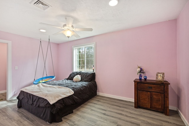 bedroom with ceiling fan, wood finished floors, visible vents, and baseboards