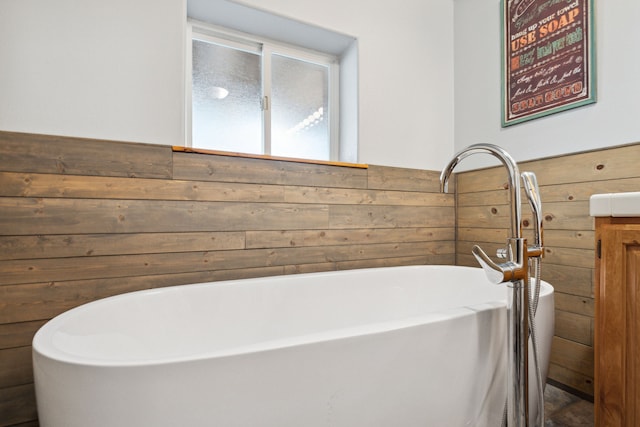 full bathroom with a wainscoted wall, a soaking tub, vanity, and wooden walls