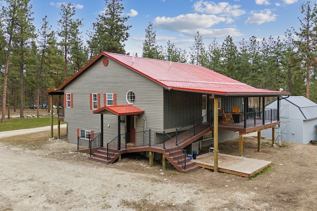 view of front facade with a deck, metal roof, and an outbuilding