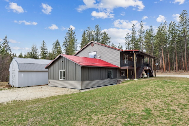 view of front of home featuring metal roof, driveway, a front lawn, and board and batten siding