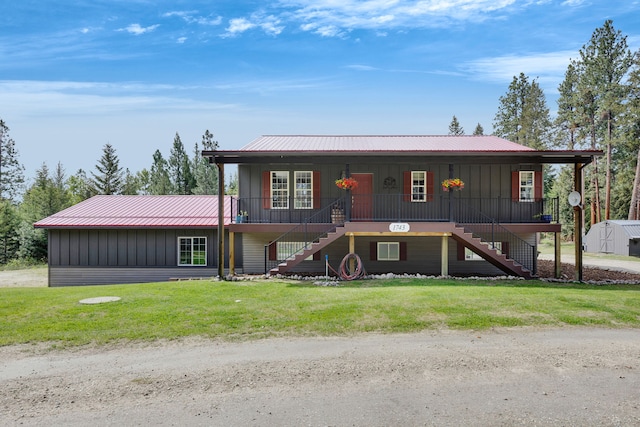 1743 Nighthawk Trl, Victor, MT 59875 - view of front facade with stairs, board and batten siding, covered porch, metal roof, and a front lawn
