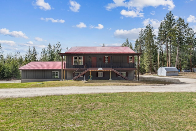 view of front of house with a porch, metal roof, a front lawn, and stairs