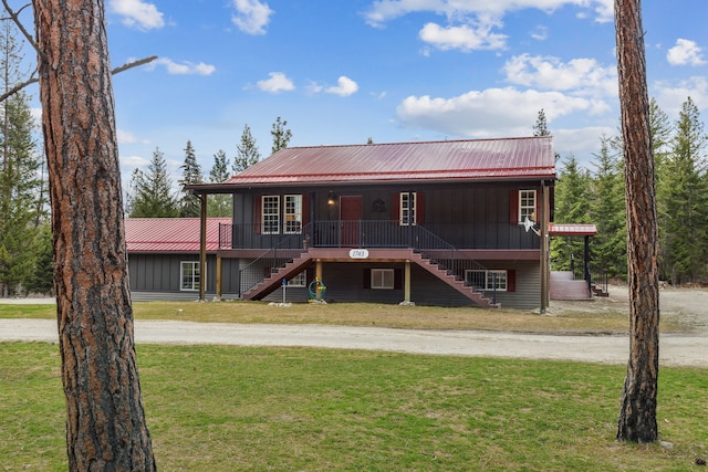 view of front of property featuring metal roof, a front lawn, stairway, and a porch