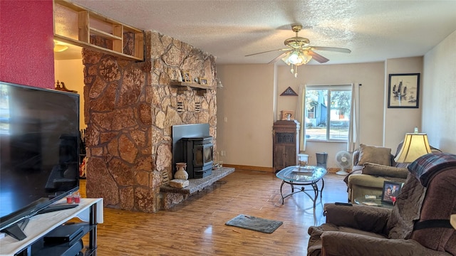 403 Dakota Ave, Libby, MT 59923 - living area featuring a wood stove, ceiling fan, wood finished floors, and a textured ceiling