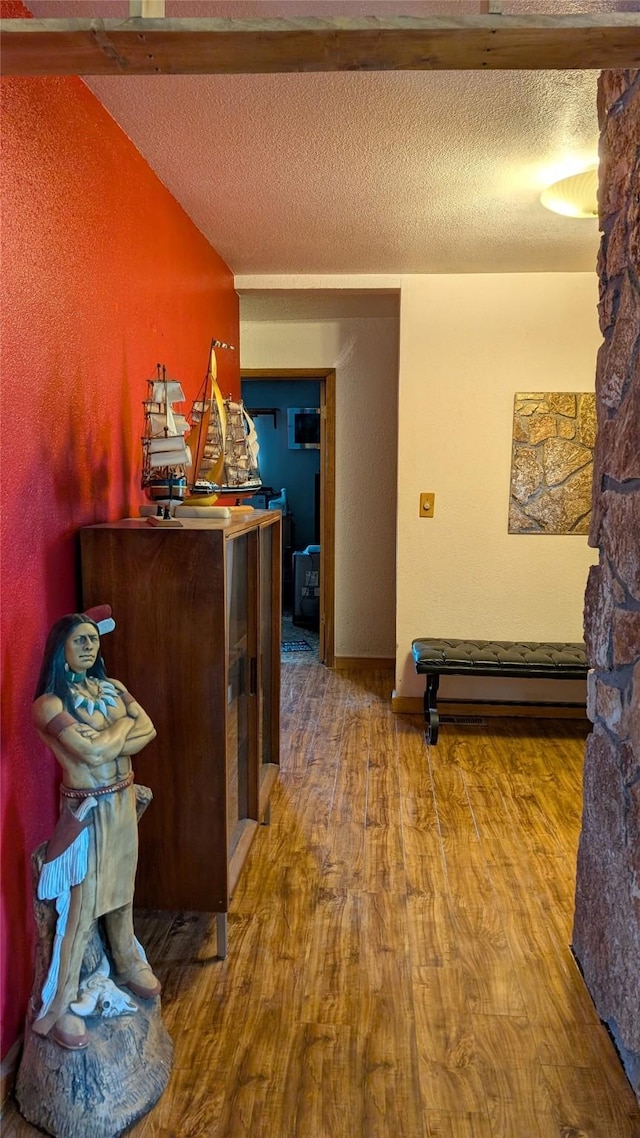 corridor featuring lofted ceiling, a textured ceiling, and wood finished floors