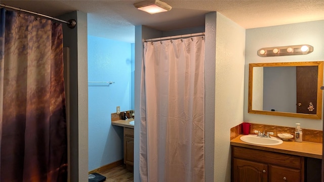 403 Dakota Ave, Libby, MT 59923 - full bath with vanity, wood finished floors, a shower with curtain, and a textured wall