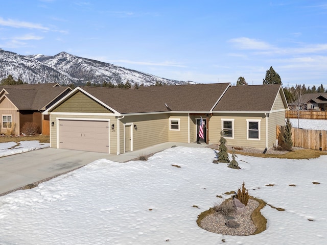 ranch-style house featuring driveway, an attached garage, fence, and a mountain view