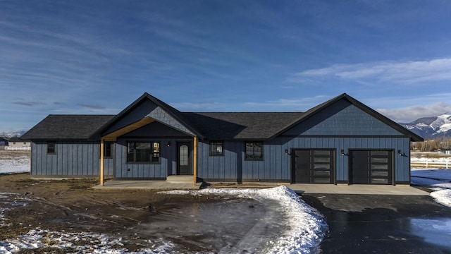 view of front of property with an attached garage, aphalt driveway, board and batten siding, and roof with shingles