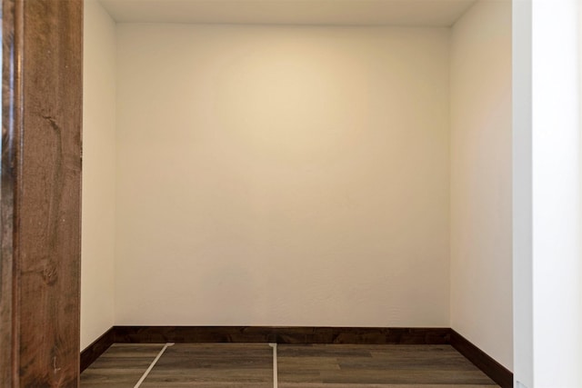 spare room featuring dark wood-style flooring and baseboards