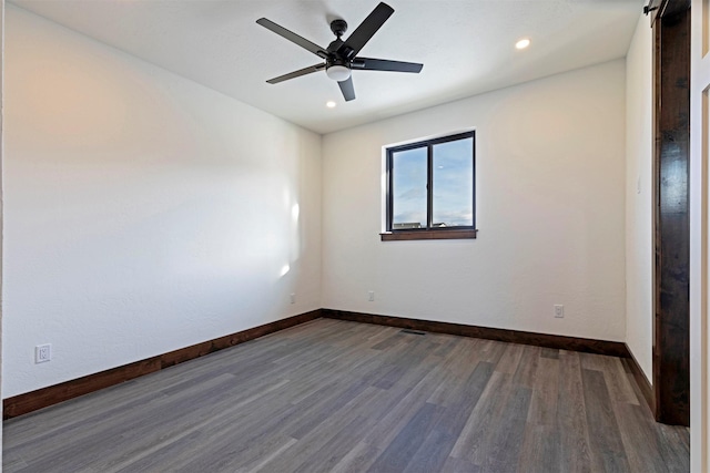 unfurnished room featuring recessed lighting, a barn door, a ceiling fan, wood finished floors, and baseboards