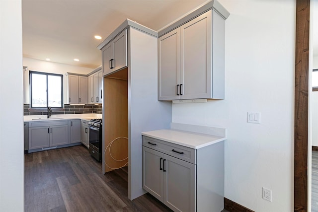 kitchen featuring gas range, gray cabinets, and a sink