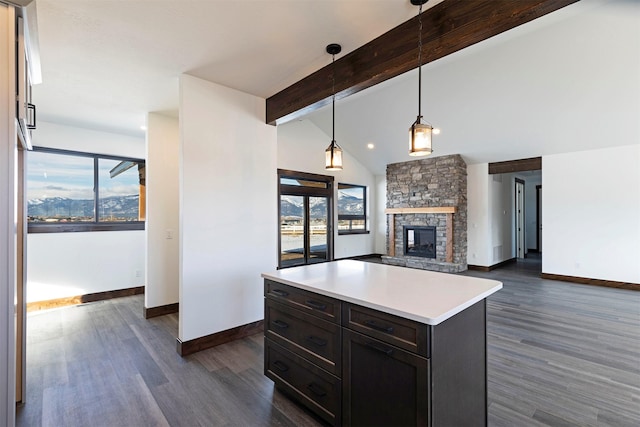 kitchen featuring dark wood-style floors, a fireplace, vaulted ceiling with beams, light countertops, and baseboards