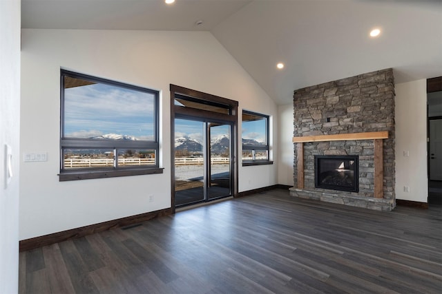 unfurnished living room with baseboards, wood finished floors, a stone fireplace, high vaulted ceiling, and recessed lighting