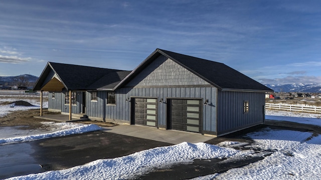 snow covered structure featuring a garage, fence, and a mountain view