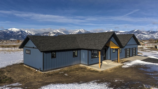 modern farmhouse featuring roof with shingles, a mountain view, and fence