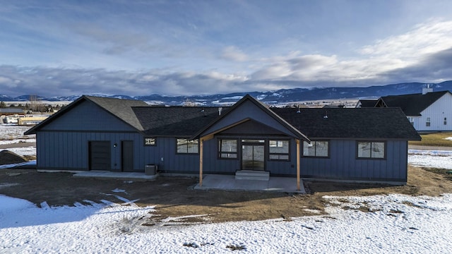 view of front of house with a patio, roof with shingles, and a mountain view