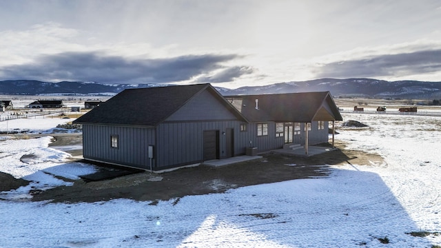 snow covered house featuring board and batten siding and a mountain view