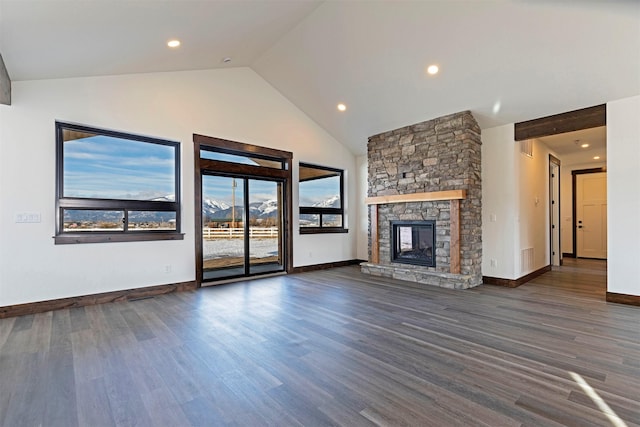 unfurnished living room featuring visible vents, baseboards, wood finished floors, a stone fireplace, and high vaulted ceiling