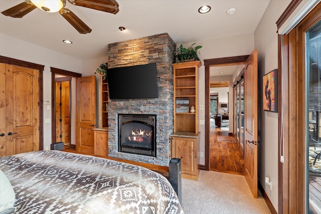 bedroom featuring recessed lighting, light colored carpet, a stone fireplace, and baseboards